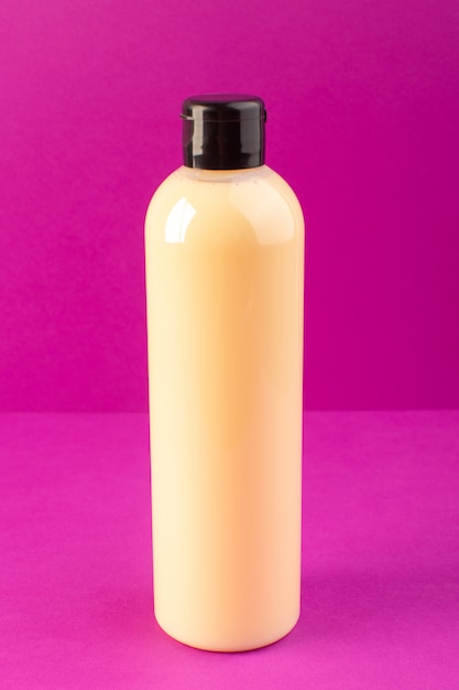 Eine cremefarbene Plastik-Shampoo-Dose mit Vorderansicht und schwarzer Kappe, die auf dem Schönheitshaar der lila Hintergrundkosmetik isoliert ist