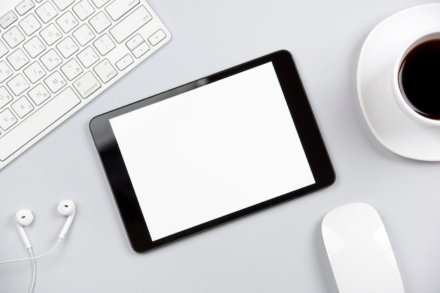Eine Draufsicht auf die Tastatur; Kopfhörer; Maus; digitale Tablette und Kaffeetasse auf grauem Hintergrund