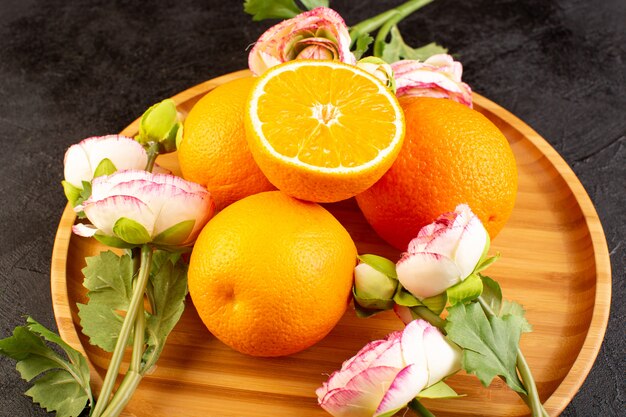Eine Draufsicht auf frische Orangen saure reife ganze und geschnittene milde tropische Zitrusvitamingelb auf dem dunklen Schreibtisch