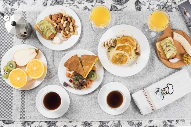 Eine Draufsicht auf Früchte; Sandwiches; Pfannkuchen; Kuchen auf Teller über Serviette