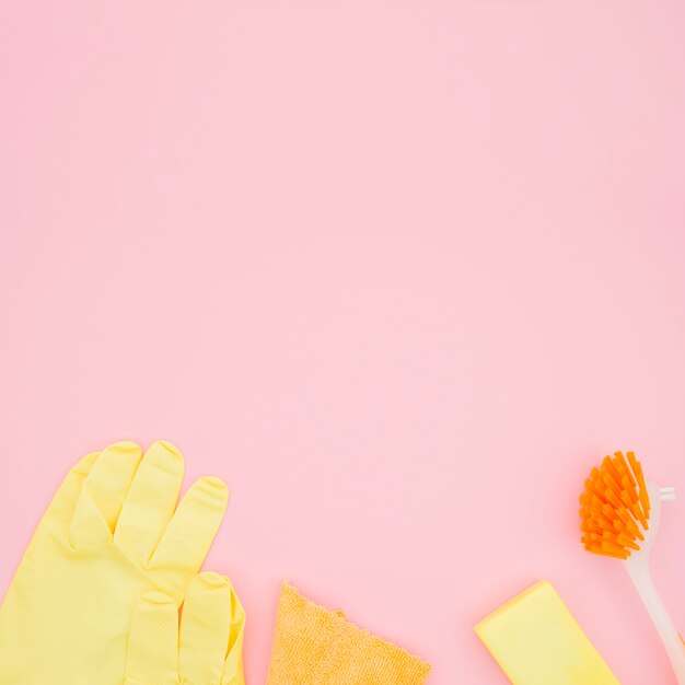 Eine Draufsicht auf Handschuhe; Bürste; Schwamm und Flasche auf rosa Hintergrund