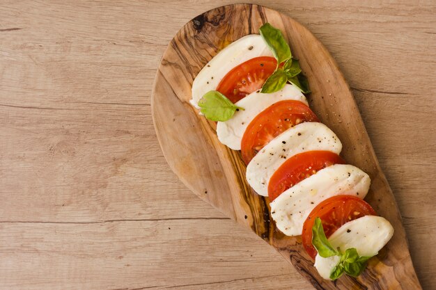 Eine Draufsicht auf italienischen Caprese-Salat mit Mozzarella-Scheiben; Basilikum und Tomaten auf Servierbrett