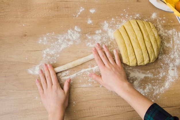 Eine Draufsicht der Frau, die selbst gemachten frischen italienischen Teigwaren Gnocchi auf Holztisch zubereitet