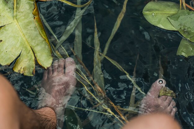 Eine Draufsicht der Füße des Mannes unter dem Teich