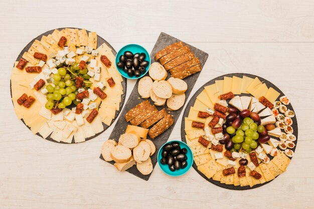 Eine Draufsicht der Käseplatte mit Scheiben brot und Oliven auf hölzernem Schreibtisch