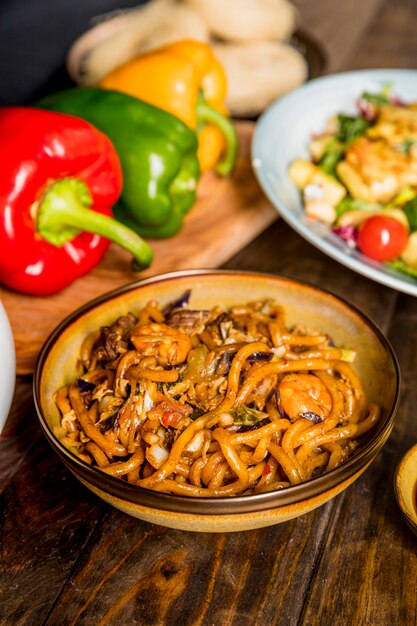 Eine Draufsicht der Schüssel mit Udon-Nudeln und Garnelen auf hölzernen Schreibtisch