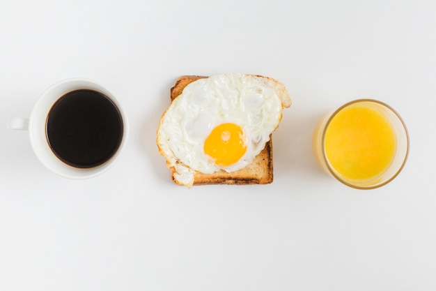 Eine Draufsicht der Teetasse; Saftglas und Toastbrot mit dem Spiegelei lokalisiert auf weißem Hintergrund