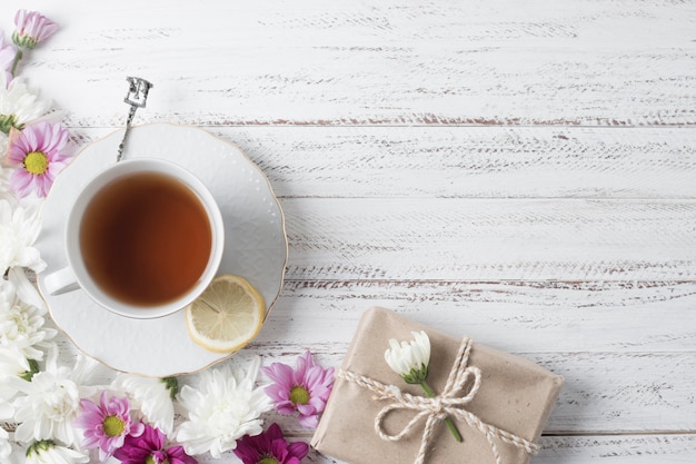 Eine Draufsicht der Zitronenteeschale verziert mit Blumen und Geschenkbox auf hölzernem Schreibtisch