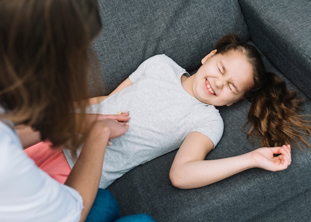 Kostenloses Foto eine draufsicht einer ärztin, die den magen ihres mädchens liegt auf grauem sofa überprüft