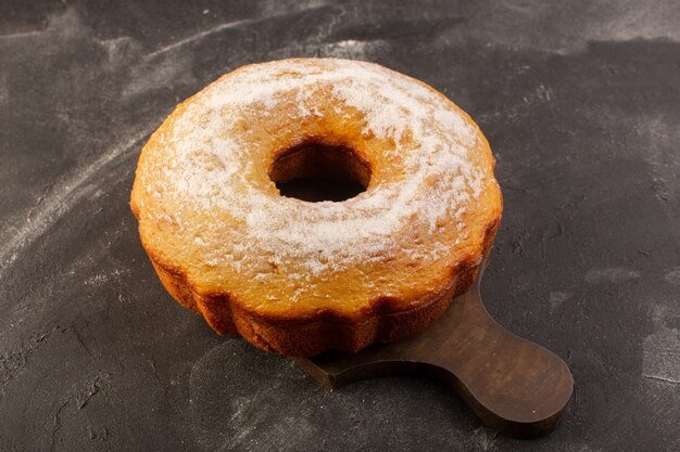 Eine Draufsicht gebackenen runden Kuchen mit Zuckerpulver auf dem hölzernen Schreibtisch