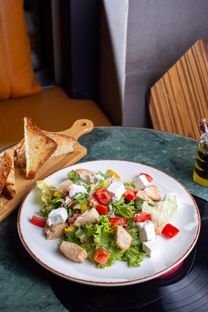 Eine Draufsicht Gemüsesalat mit Hühnerscheiben und Brot auf dem grünen Tisch Essen Mahlzeit Gemüse