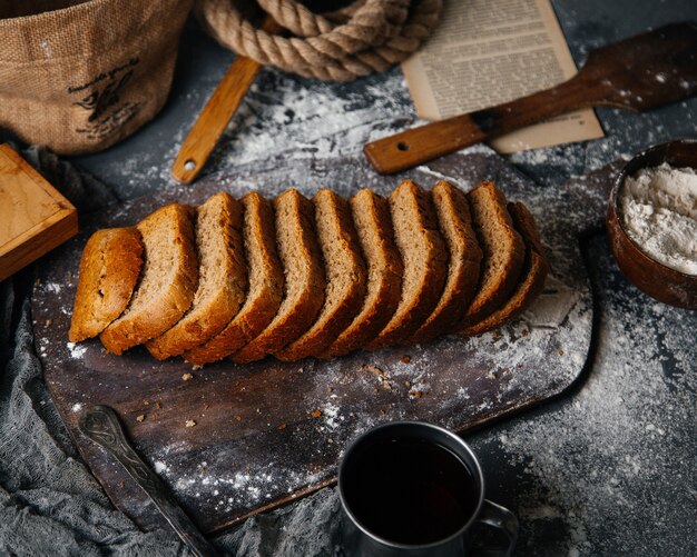 Eine Draufsicht geschnittenes graues Brot, das auf dem grauen Schreibtischbrotbrötchen-Nahrungsmittelmehlteigfoto gebacken wird