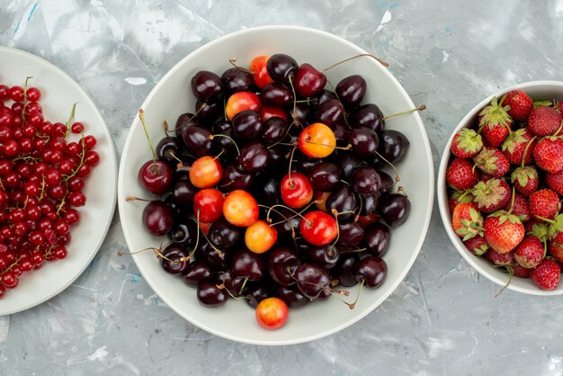 Eine Draufsicht Kirschen und Erdbeeren mit Preiselbeeren innerhalb weißer Platte