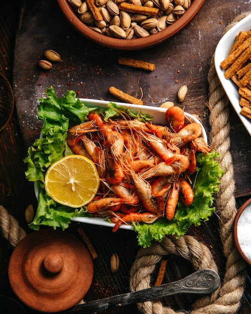 Eine Draufsicht kochte Garnelen mit grünem Salat und Zitrone auf der hölzernen Tischnahrungsmahlzeit Meeresfrüchte