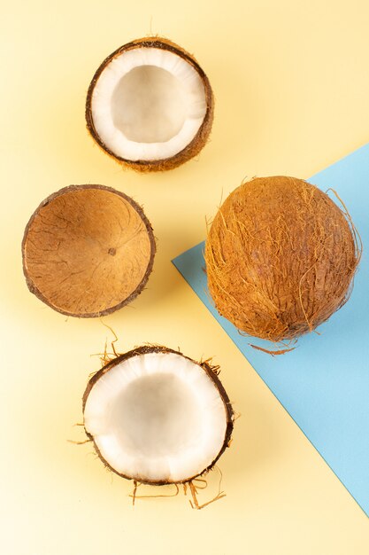 Eine Draufsicht Kokosnüsse ganz und in Scheiben geschnitten milchig frisch weich auf der creme-eisblau gefärbten Farbe