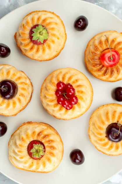 Eine Draufsicht leckere kleine Kuchen mit Beeren und Früchten innerhalb Tellerkuchen Keks Zucker Backofen