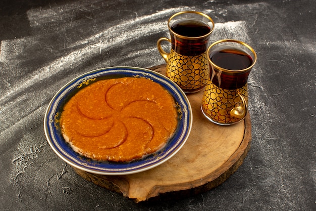 Eine Draufsicht süßes köstliches halva leckeres östliches süßes Dessert innerhalb Platte mit Tee auf der dunklen Oberfläche