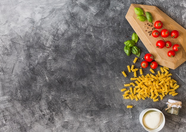 Eine Draufsicht von rohen Fusilli mit Zutaten über den Grunge-Hintergrund