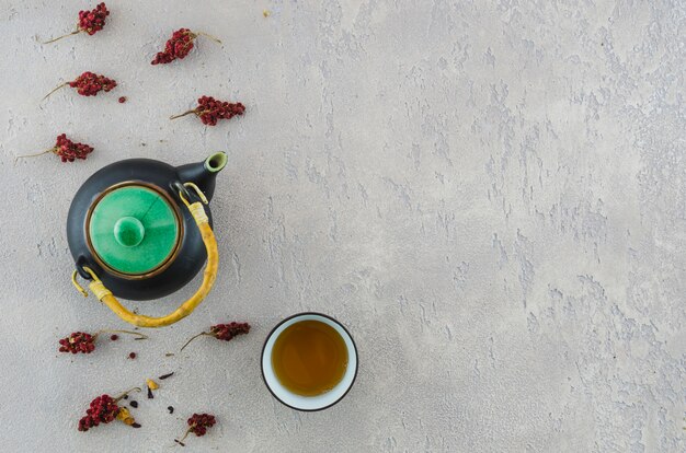 Eine erhöhte Ansicht der orientalischen Teekanne und der Kräuterteeschale mit Kräutern auf Beschaffenheitshintergrund