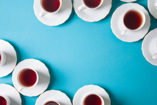 Eine erhöhte Ansicht des weißen Kräutertees in der keramischen Tasse und Untertasse auf blauem Hintergrund