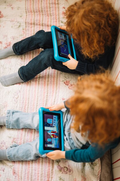 Eine erhöhte Ansicht von den Kleinkindern, die Video auf digitaler Tablette aufpassen