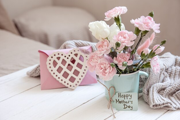 Eine festliche Komposition mit frischen Blumen in einer Vase, dekorativen Elementen und dem Wunsch nach Frohen Ostern auf einer Postkarte.