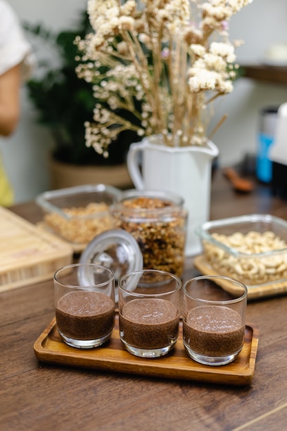 Eine Frau bereitet in der Küche Chia-Pudding zu und legt die unterste Schicht aus Mandelmilch, Kakao und Chia-Samen aus.