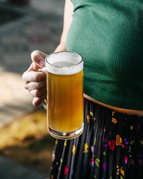 Eine Frau der Vorderansicht, die Biereis und kaltes außerhalb Alkoholgetränk hält