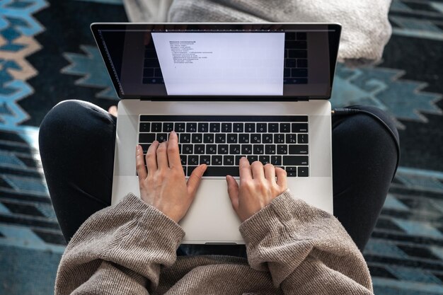 Eine Frau, die an einer Draufsicht des Laptops sitzt