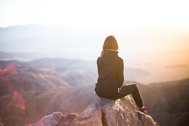 Eine Frau, die auf einem Berggipfel sitzt