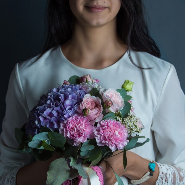 Eine Frau, die einen Blumenstrauß der purpurroten und rosa Blumenkombination in der Hand hält