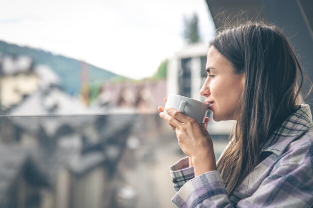 Eine Frau, die morgens auf dem Balkon Kaffee trinkt