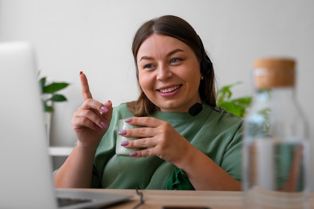 Eine Frau, die zu Hause einen Videoanruf auf einem Laptop mit Headset macht