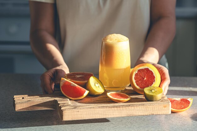 Eine Frau hält in der Küche ein Glas frisch gepressten Saft in den Händen