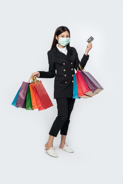 Eine Frau im Dunkeln und mit Maske geht einkaufen, trägt Kreditkarten und viele Taschen