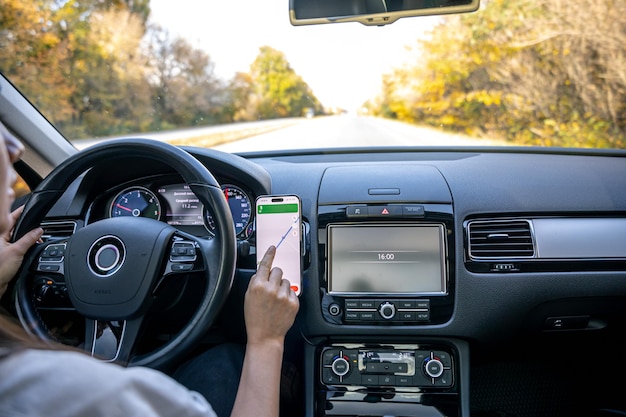 Eine Frau in einem Auto hält ein Mobiltelefon mit einer GPS-Navigationskarte