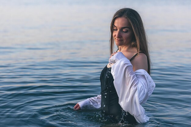 Eine Frau in einem Badeanzug und einem weißen Hemd im Meer