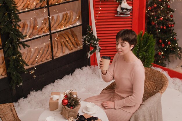 Eine frau in einem café trinkt kaffee oder tee. weihnachts- und neujahrskonzept.