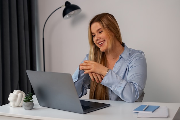 Kostenloses Foto eine frau in mittlerer einstellung führt videoanrufe mit einem laptop