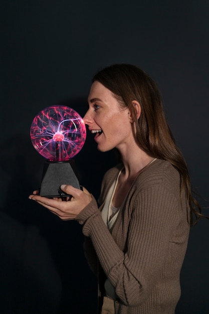 Eine Frau in mittlerer Einstellung interagiert mit einer Plasmakugel