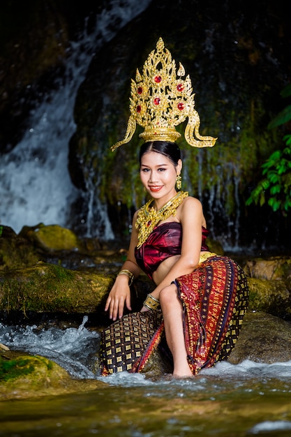 Kostenloses Foto eine frau kleidete sich mit einem alten thailändischen kleid am wasserfall an.