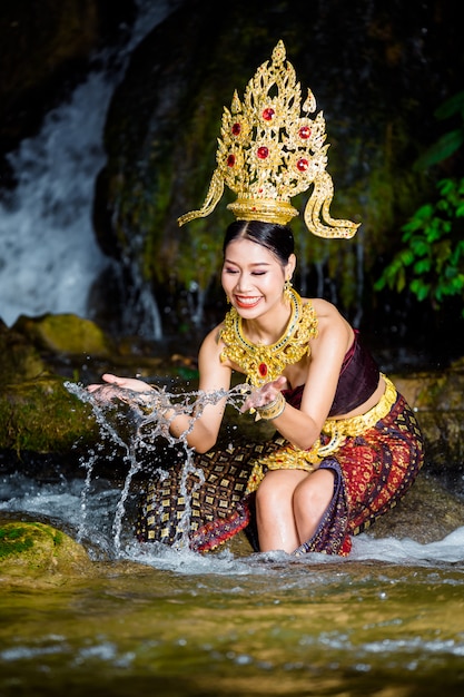 Eine Frau kleidete sich mit einem alten thailändischen Kleid am Wasserfall an.