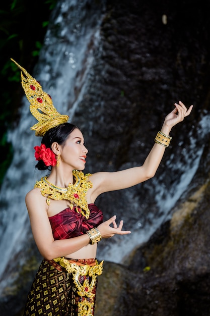 Kostenloses Foto eine frau kleidete sich mit einem alten thailändischen kleid am wasserfall an.