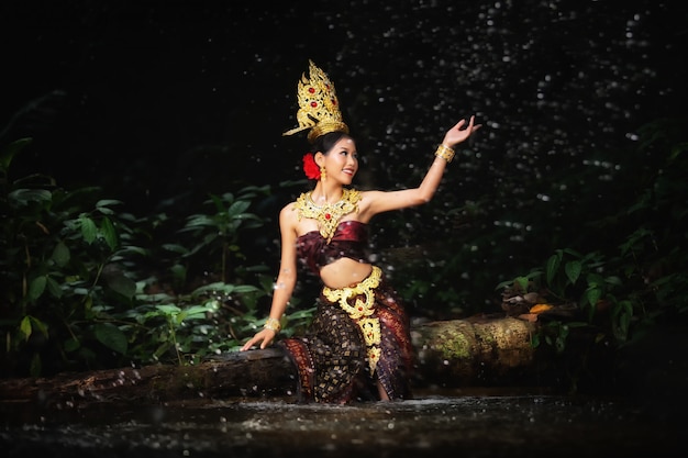 Kostenloses Foto eine frau kleidete sich mit einem alten thailändischen kleid am wasserfall an.