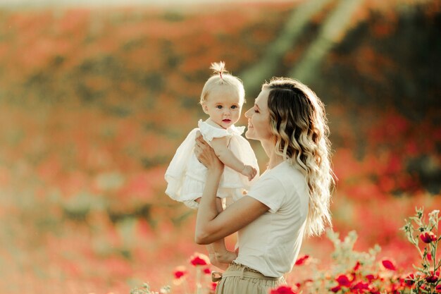 Eine Frau lächelt einem Baby auf dem Mohnblumenfeld zu