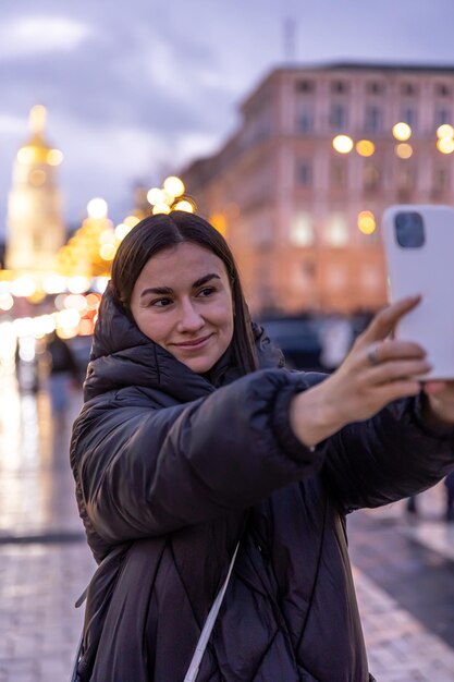 Eine Frau macht ein Foto vor dem Hintergrund der Nachtstadt auf einem Smartphone