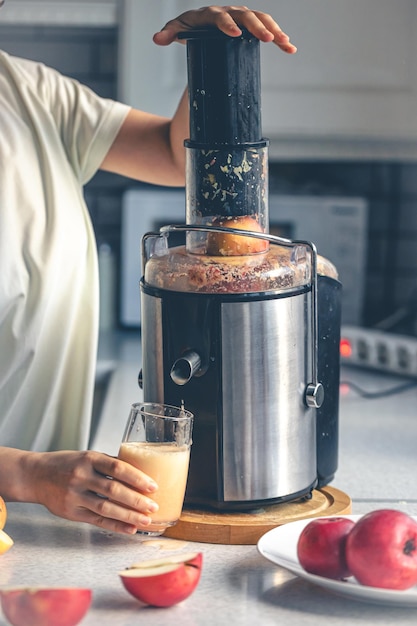 Kostenloses Foto eine frau macht zu hause apfelsaft mit einer saftpresse