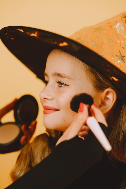 Eine Frau malt auf das Gesicht des Mädchens ein Make-up eines Kätzchens für eine Party auf Haloween