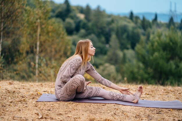 Eine Frau praktiziert Yoga am Morgen in einem Park an der frischen Luft.