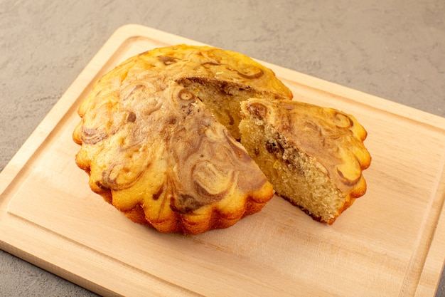 Eine Front geschlossene Ansicht süßen Kuchen köstlichen leckeren Schokoladenkuchen auf dem cremefarbenen quadratischen Schreibtisch geschnitten